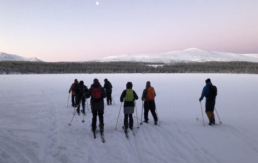 Grupp med skidåkare på Nulltjärn en iskall midvinterdag med blekrosa himmel och vita fjäll i bakgrunden