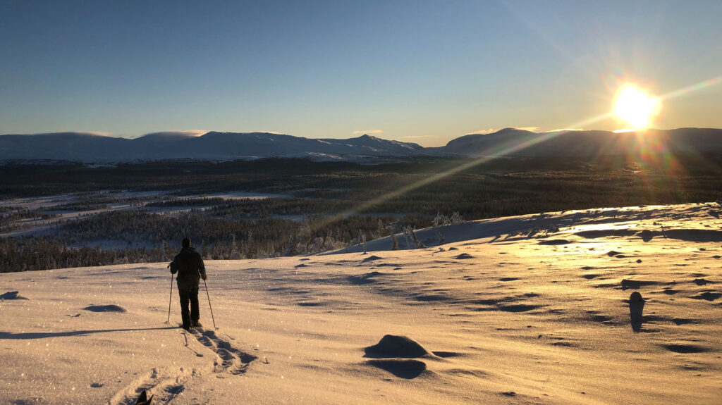 Snöskovandrare på kalfjäll med utsikt över Lunndörrspasset